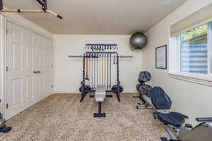 Exercise area with a textured ceiling and light colored carpet