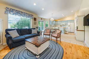 Living room with a chandelier, light hardwood / wood-style floors, and vaulted ceiling