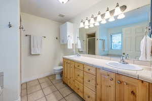 Bathroom featuring vanity, toilet, an enclosed shower, and tile patterned floors