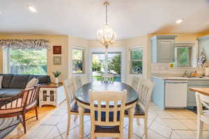 Tiled dining room featuring sink and a notable chandelier