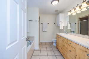 Full bathroom featuring vanity, toilet, tile patterned floors, and shower with separate bathtub