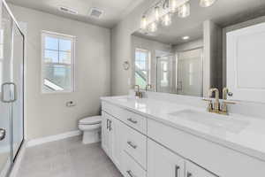 Bathroom featuring vanity, toilet, a wealth of natural light, and an enclosed shower