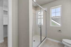 Bathroom with tile patterned floors, toilet, and a shower with shower door