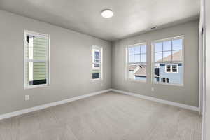 Empty room with light carpet and a textured ceiling
