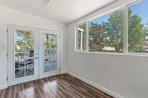 Entryway featuring dark wood-type flooring, a wealth of natural light, and french doors