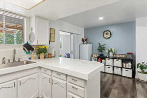 Kitchen with backsplash, kitchen peninsula, sink, dark hardwood / wood-style floors, and white cabinets