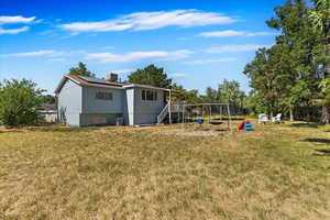 Back of property with a lawn, solar panels, and a playground