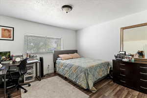 Bedroom featuring a textured ceiling and dark hardwood / wood-style floors