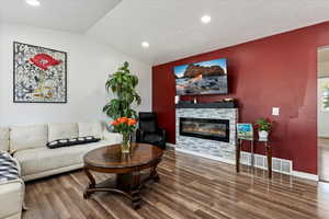 Living room with dark wood-type flooring, lofted ceiling, and a textured ceiling