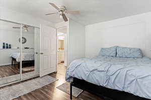 Bedroom with a closet, ceiling fan, dark hardwood / wood-style flooring, and a textured ceiling