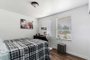 Bedroom featuring a textured ceiling and dark hardwood / wood-style flooring