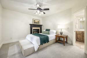 Bedroom with light colored carpet, ceiling fan, and ensuite bath