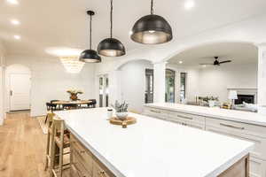 Kitchen featuring pendant lighting, white cabinetry, decorative columns, ceiling fan, and light hardwood / wood-style floors