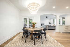 Dining space featuring light wood-type flooring, ornamental molding, ceiling fan, and decorative columns