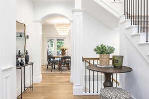 Corridor featuring lofted ceiling, light hardwood / wood-style floors, and a notable chandelier