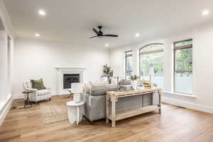 Living room featuring ceiling fan, ornamental molding, and light hardwood / wood-style flooring