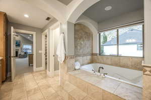 Bathroom with tile patterned flooring, plenty of natural light, and tiled tub