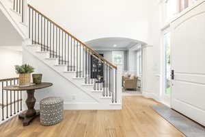 Entrance foyer featuring a towering ceiling, plenty of natural light, ornamental molding, and light hardwood / wood-style flooring