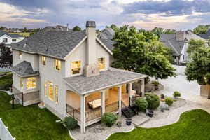 Back house at dusk featuring a lawn and a patio area