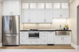 Basement Kitchen with light wood-type flooring, white cabinets, and stainless steel appliances