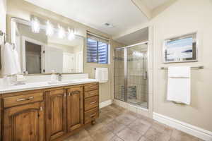 Bathroom with tile patterned flooring, a shower with door, a textured ceiling, and vanity