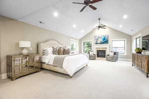 Carpeted bedroom featuring a fireplace, vaulted ceiling, and ceiling fan