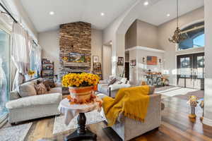 Living room with high vaulted ceiling, a wealth of natural light, hardwood / wood-style flooring, and a fireplace