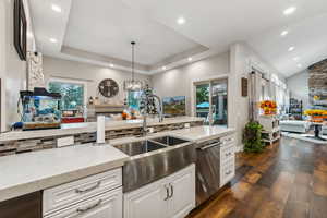 Kitchen with dark wood-type flooring, white cabinets, plenty of natural light, and sink