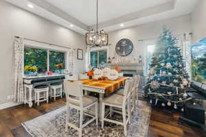 Dining room with a tray ceiling, a chandelier, and dark hardwood / wood-style floors