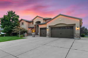 Mediterranean / spanish-style home with a lawn and a garage