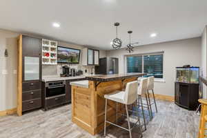 Kitchen featuring decorative light fixtures, appliances with stainless steel finishes, a breakfast bar, a center island, and light wood-type flooring