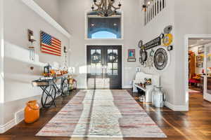 Foyer featuring french doors, dark wood-type flooring, and a high ceiling