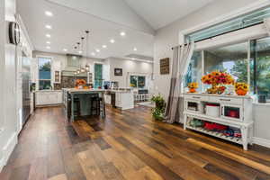 Kitchen with white cabinetry, lofted ceiling, dark hardwood / wood-style floors, a breakfast bar area, and a kitchen island