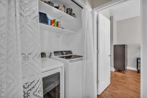 Laundry area with washing machine and clothes dryer and light hardwood / wood-style floors