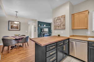 Kitchen featuring decorative light fixtures, dishwasher, wooden counters, light brown cabinets, and light hardwood / wood-style floors