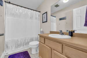 Bathroom with vanity, toilet, walk in shower, and tile patterned flooring