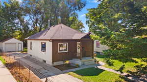 Bungalow with an outdoor structure, a garage, and a front lawn