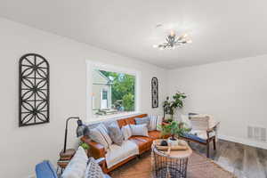 Living room with hardwood / wood-style flooring and an inviting chandelier