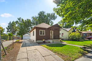 View of front of house featuring a garage, a front lawn, and an outdoor structure