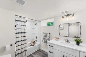 Bathroom featuring vanity, a textured ceiling, hardwood / wood-style floors, and shower / bathtub combination with curtain