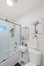 Full bathroom featuring shower / bath combination with glass door, hardwood / wood-style floors, toilet, and sink