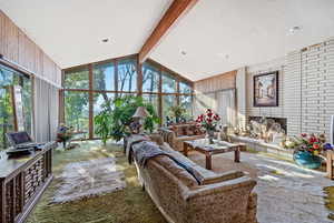 Living room with a textured ceiling, high vaulted ceiling, beam ceiling, and carpet flooring