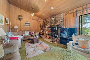 Living room featuring vaulted ceiling, carpet floors, wooden ceiling, and a brick fireplace