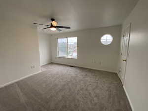 Carpeted empty room featuring ceiling fan and a wealth of natural light