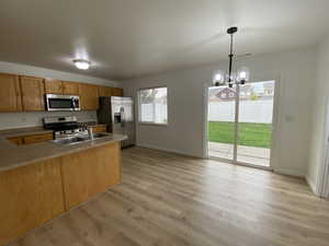 Kitchen featuring appliances with stainless steel finishes, a chandelier, light hardwood / wood-style floors, and pendant lighting