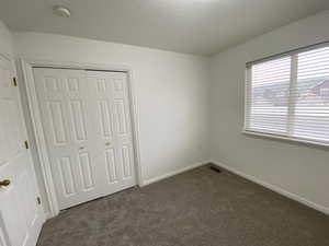 Unfurnished bedroom with dark colored carpet and a closet