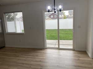 Unfurnished dining area with light hardwood / wood-style flooring and a notable chandelier