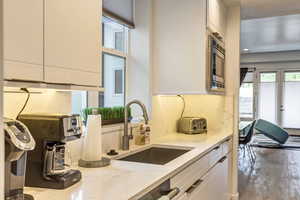 Kitchen with light stone countertops, sink, and white cabinets