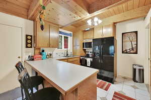 Kitchen with light tile patterned floors, an inviting chandelier, wood ceiling, stainless steel appliances, and kitchen peninsula