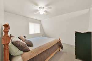 Bedroom with lofted ceiling, ceiling fan, and light carpet